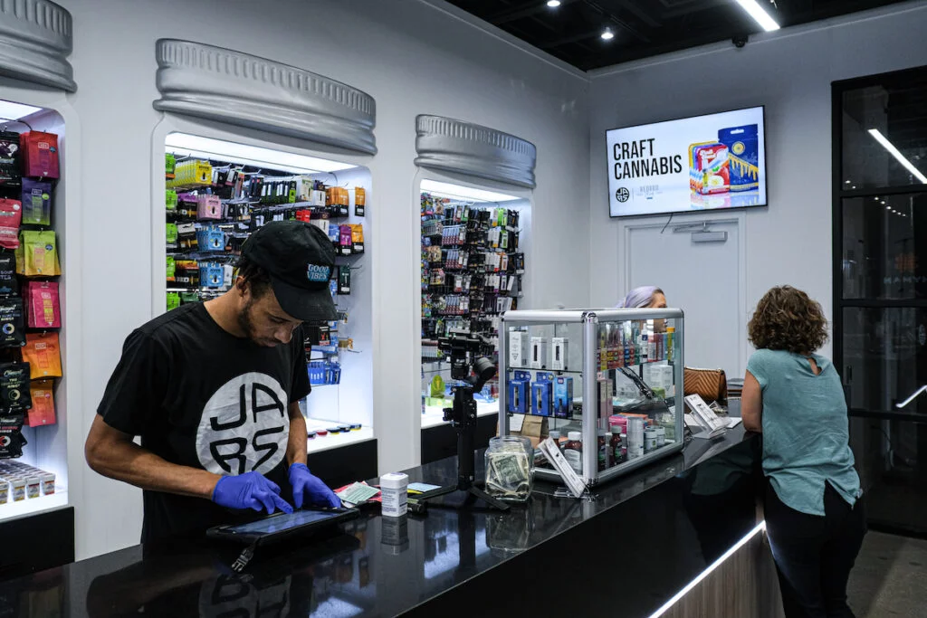 a shopper at a cannabis dispensary looks at a TV screen hanging on the wall